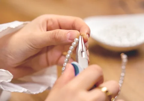 Joyero montando un collar de perlas naturales para mostrar cómo influyen los distintos tipos de perlas en el valor de una joya